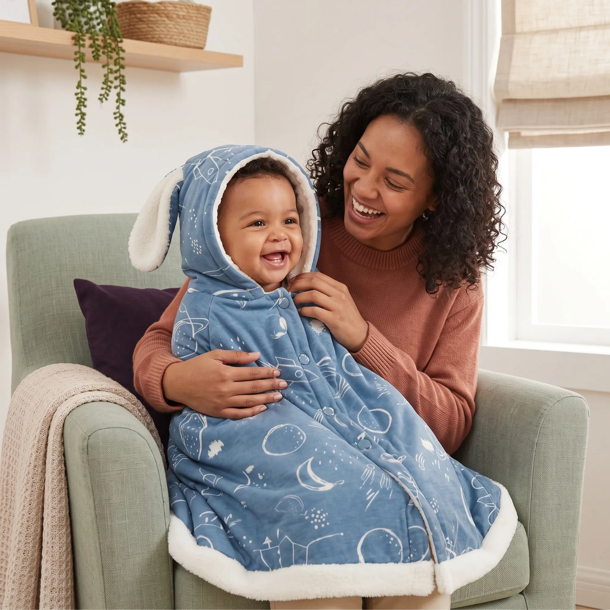 Laughing baby wrapped in the Outer Space hooded cloak with bunny ears, cuddled by a parent