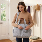 Parent carrying the light grey quilted changing bag tote on the shoulder strap with the dummy pouch attached