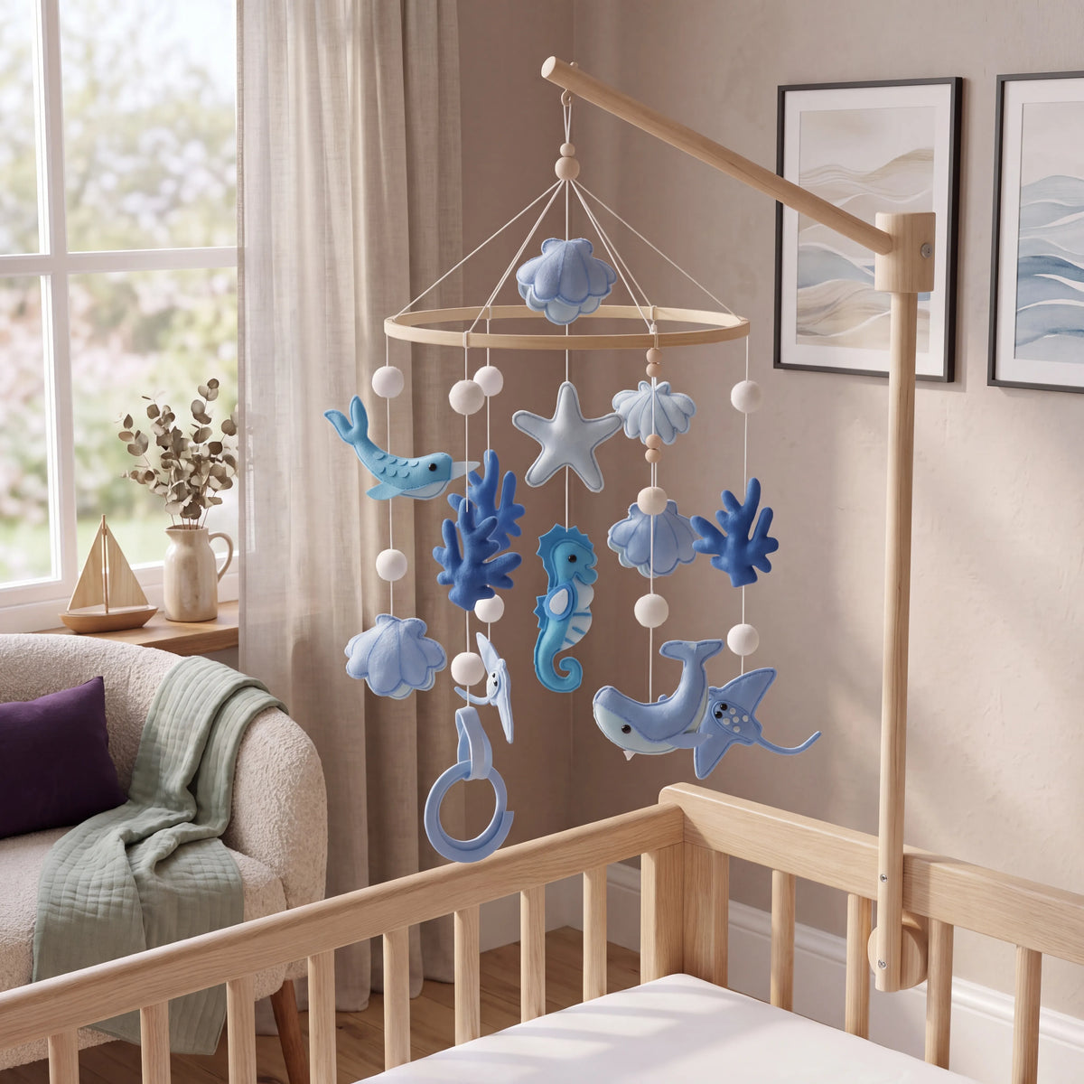 Ocean themed felt and wooden bead cot mobile with whales, starfish and seahorses hanging above a wooden cot