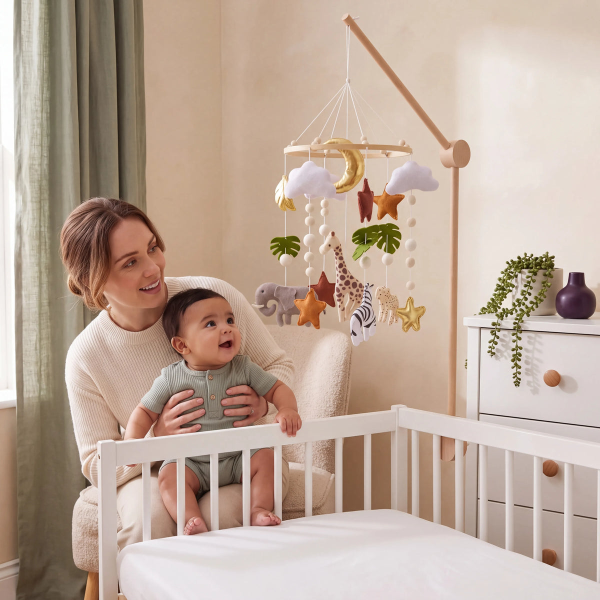 Mum and baby looking up at the Safari themed felt cot mobile with giraffe, elephant and stars