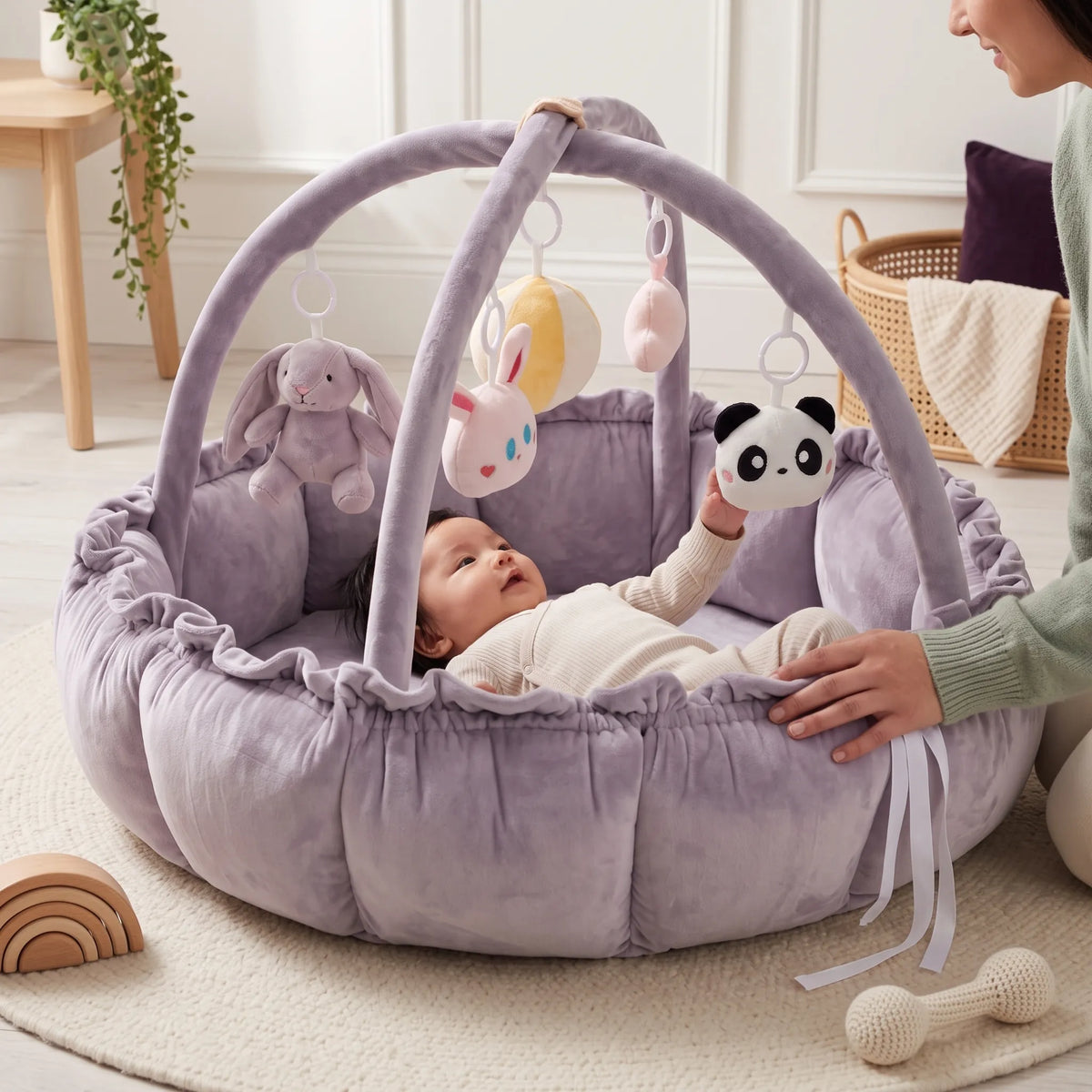 Baby reaching for a hanging panda toy in the lavender play gym nest