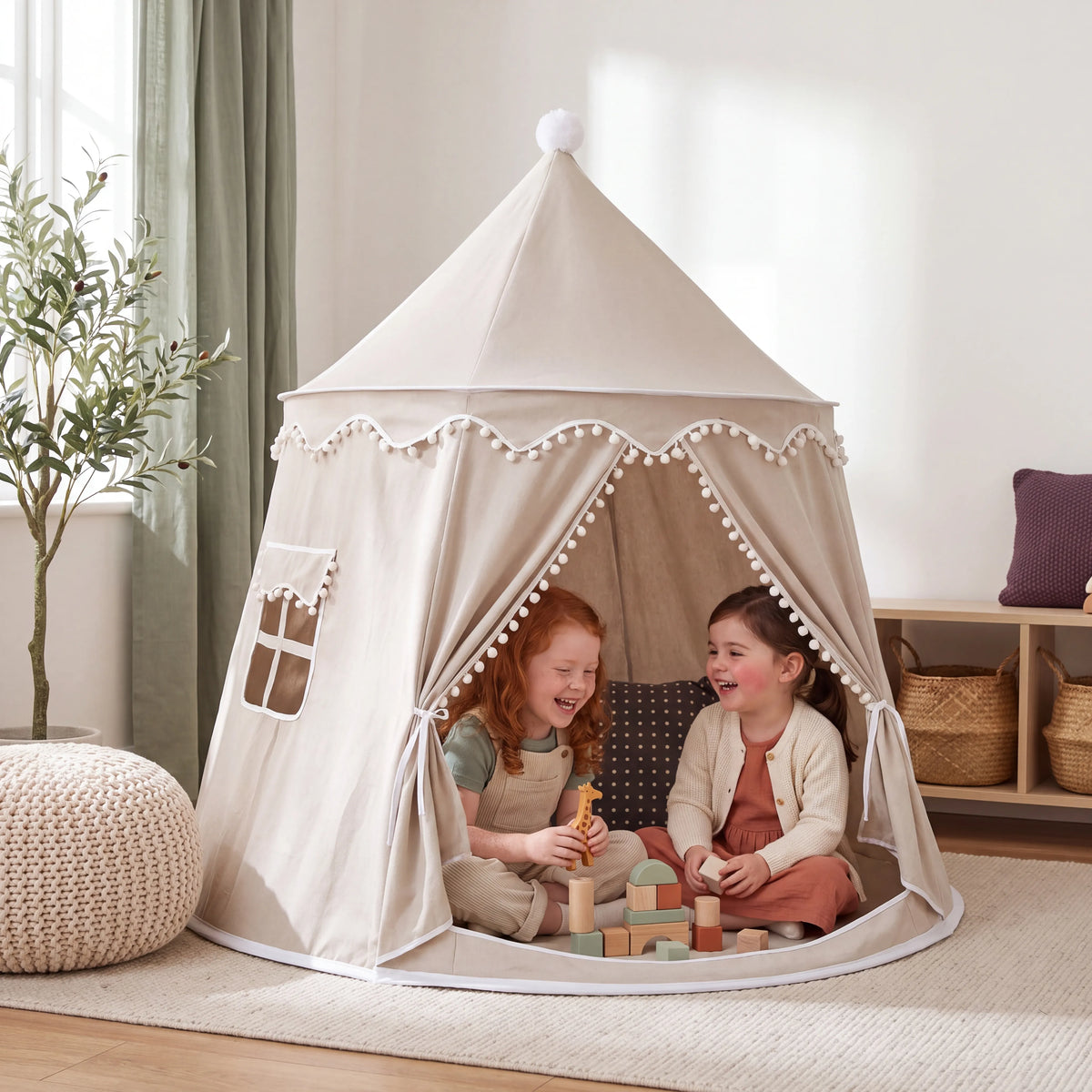 Two girls playing with wooden blocks inside the light beige kids play tent with pom-pom trim
