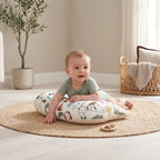 Baby reaching for a wooden toy during tummy time on the Jungle pillow