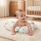 Smiling baby on their tummy on the Green Dinosaur tummy time pillow